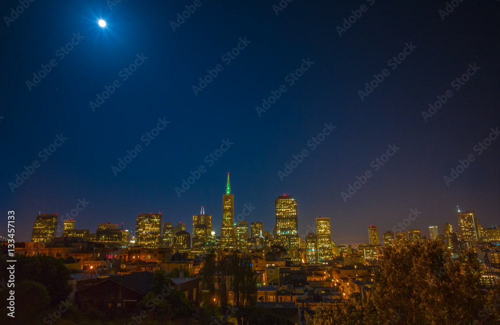 Fototapeta premium San Francisco cityscape and a full moon at night, taken from Coit Tower. Downtown and the financial district