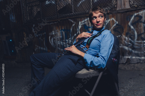 Young androgynous woman dressed in mens clothing in a grungy, urban outdoor location