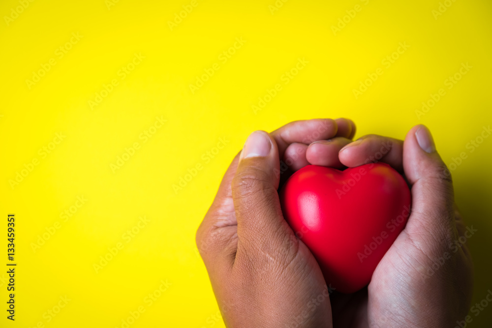 Fototapeta premium man hands giving red heart on yellow background