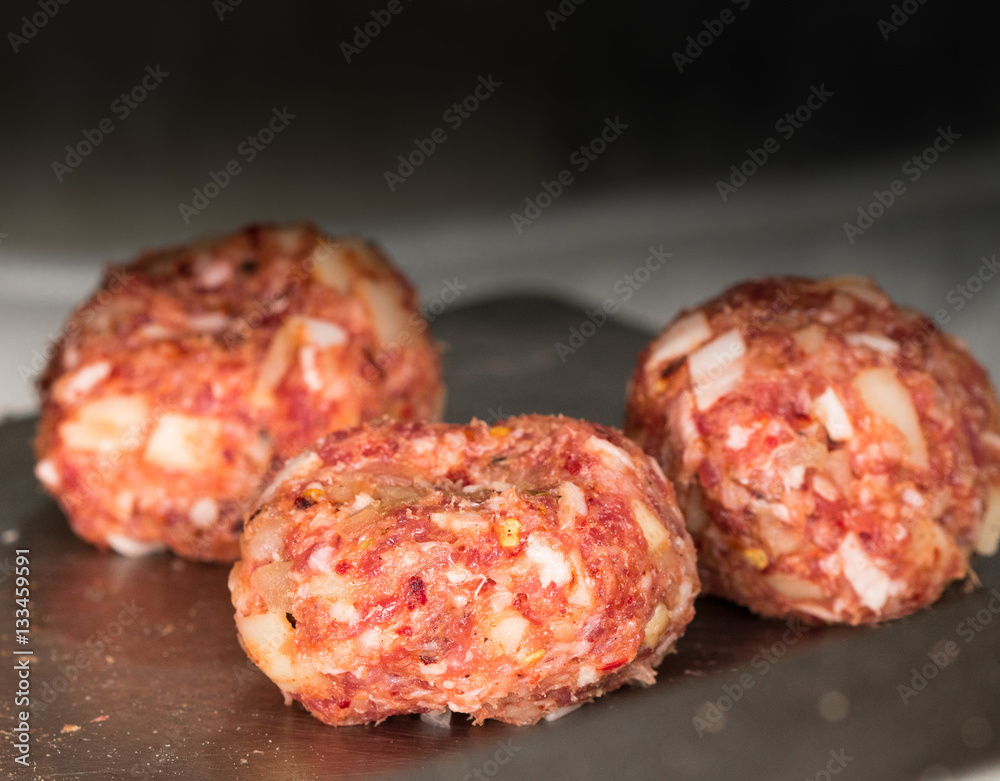 Minced meatballs with onions, bacon bits and spicy seasoning, shot close up