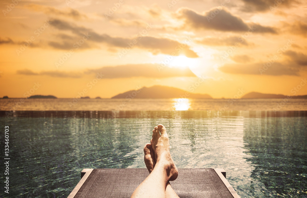 Relaxing in summer, a man laying on sunbathing bed on the island in sunset Relaxing in summer, a man laying on sunbathing bed on the island in sunset