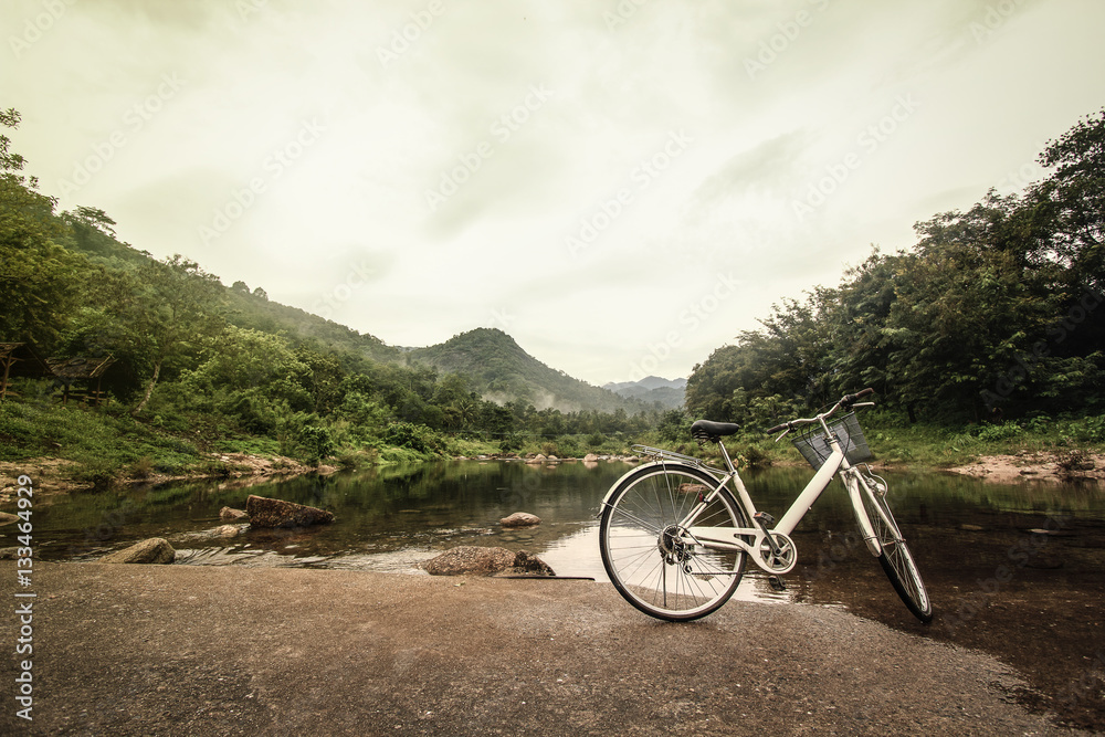 Fototapeta premium Bicycle on the bridge cross over river : Khiriwong Fuit Village ,Nakhon Si Thammarat Thailand (disappointed holiday concept ; vintage style) 