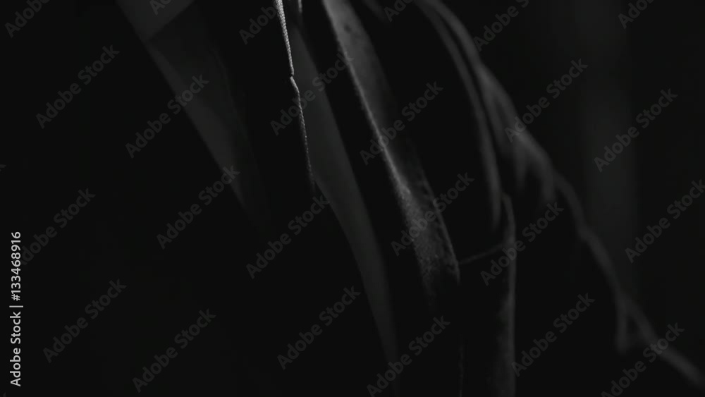 Tilt up of young stylish businessman in formal suit lokking at wrist watch in dark studio Tilt up of young stylish businessman in formal suit lokking at wrist watch in dark studio