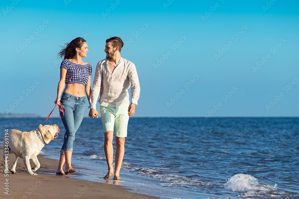 two young people running on the beach kissing and holding tight with dog two young people running on the beach kissing and holding tight with dog