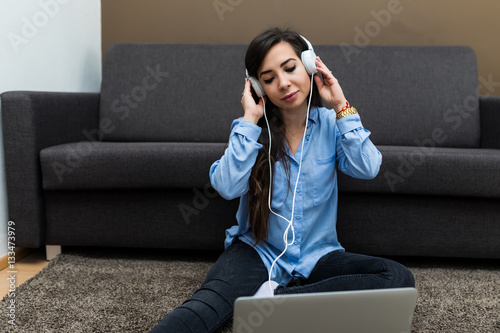 Young brunette woman lying on carpet and listen music photo