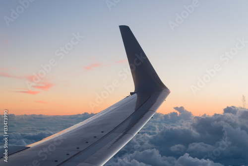 Wing of a Airplane at sunset with clouds.