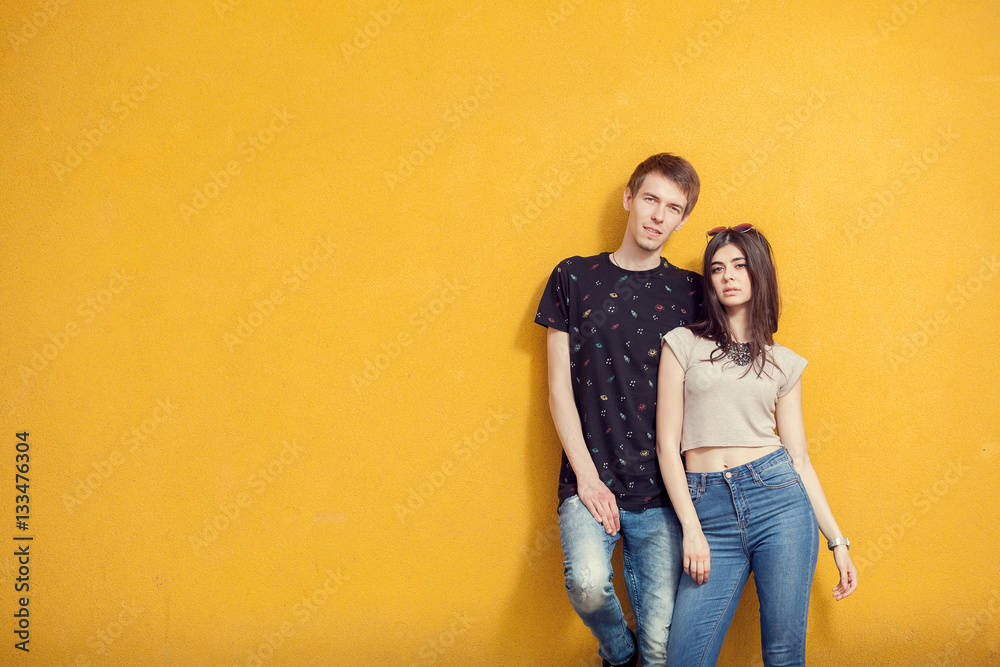 Couple posing in fashion style on yellow wall