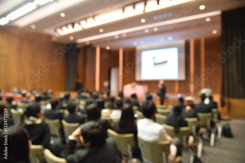 Blurred image of education people and business people sitting in conference room for profession seminar and the speaker is presenting new technology and idea sharing with the content activity.