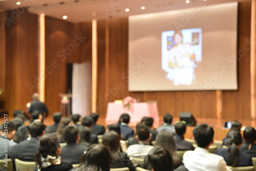 Blurred image of education people and business people sitting in conference room for profession seminar and the speaker is presenting new technology and idea sharing with the content activity.