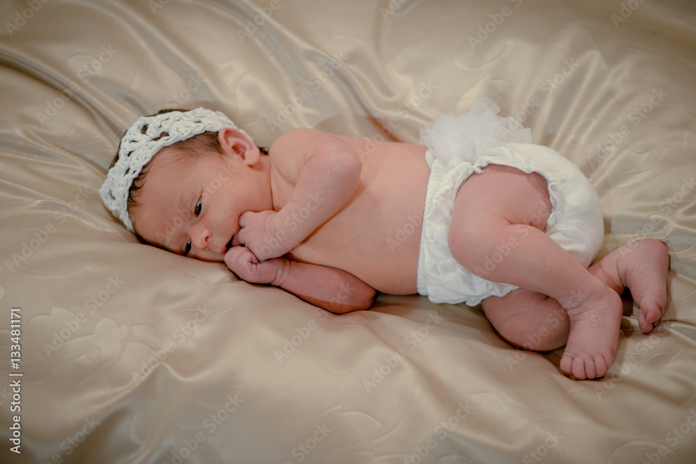 Portrait of a newborn baby infant toddler in bed. Close up top view