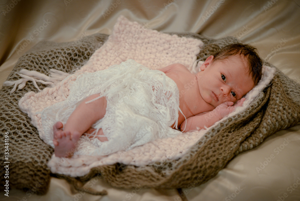 Portrait of a newborn baby infant toddler in bed. Close up top view