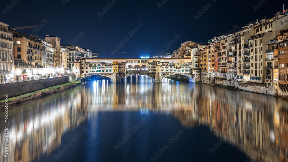 Ponte Vecchio at night is reflected in the Arno river in Florence, Italy
