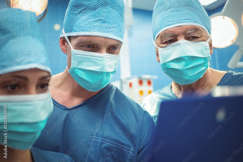 Team of surgeons discussing over clipboard in operation theater Team of surgeons discussing over clipboard in operation theater