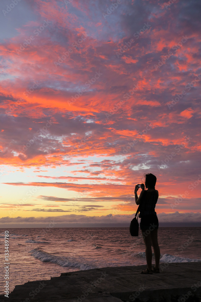 Woman Taking Beautiful Sunset photos on the beach