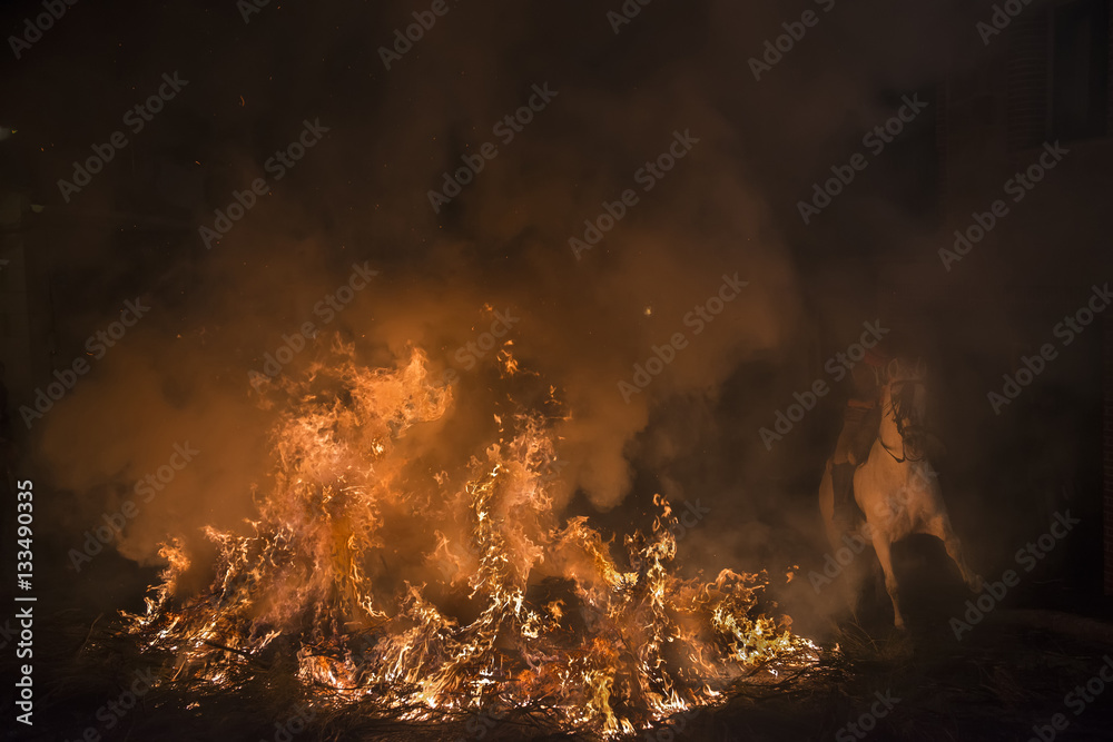 Caballos saltando hogueras de fuego en la noche de las luminarias para celebrar el día de San Antón, patrón de los animales en el pueblo de San  bartolomé de Pinares en España