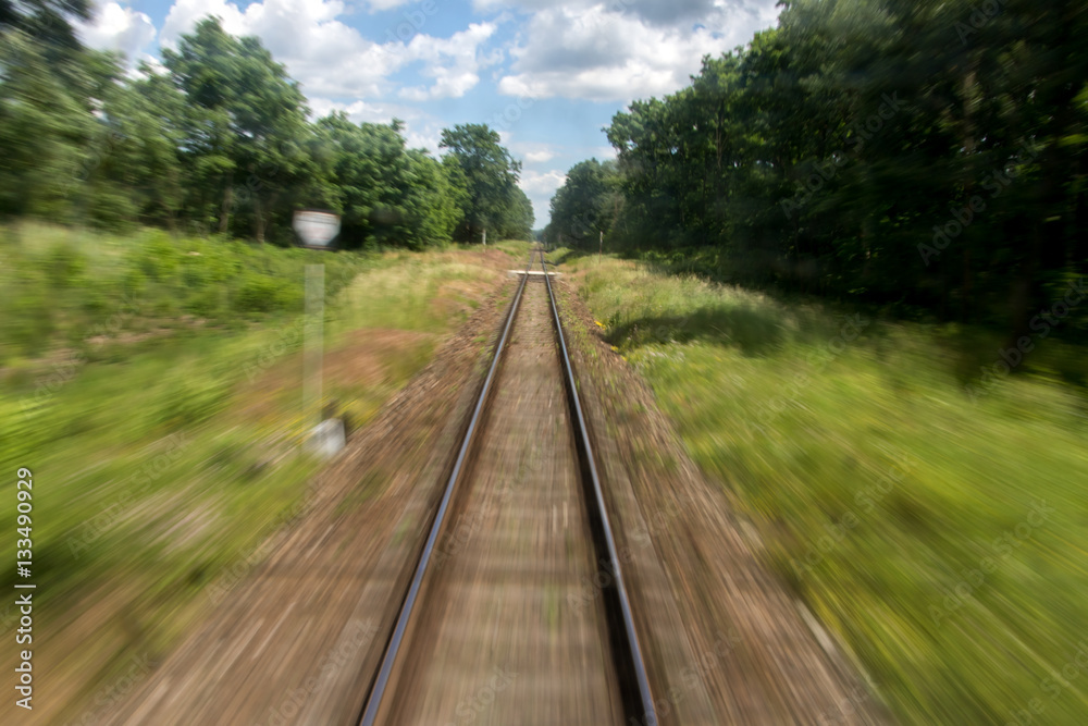 Defocused railroad tracks in summer nature behind a passing train