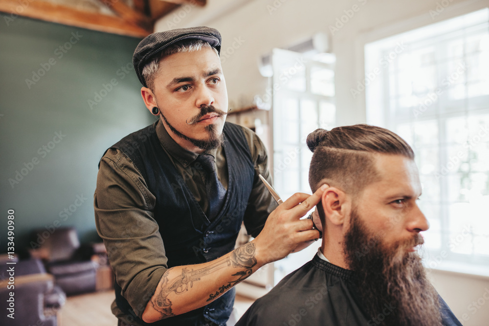 Fototapeta premium Bearded man getting haircut by barber