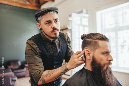 Bearded man getting haircut by barber