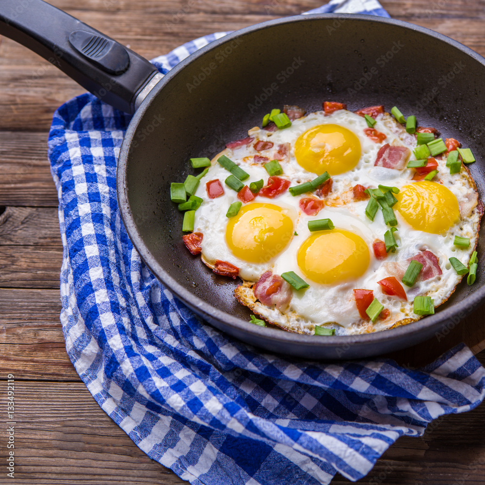 Fried eggs in pan with tomatoes and green fresh onion. Fried eggs in pan with tomatoes and green fresh onion.