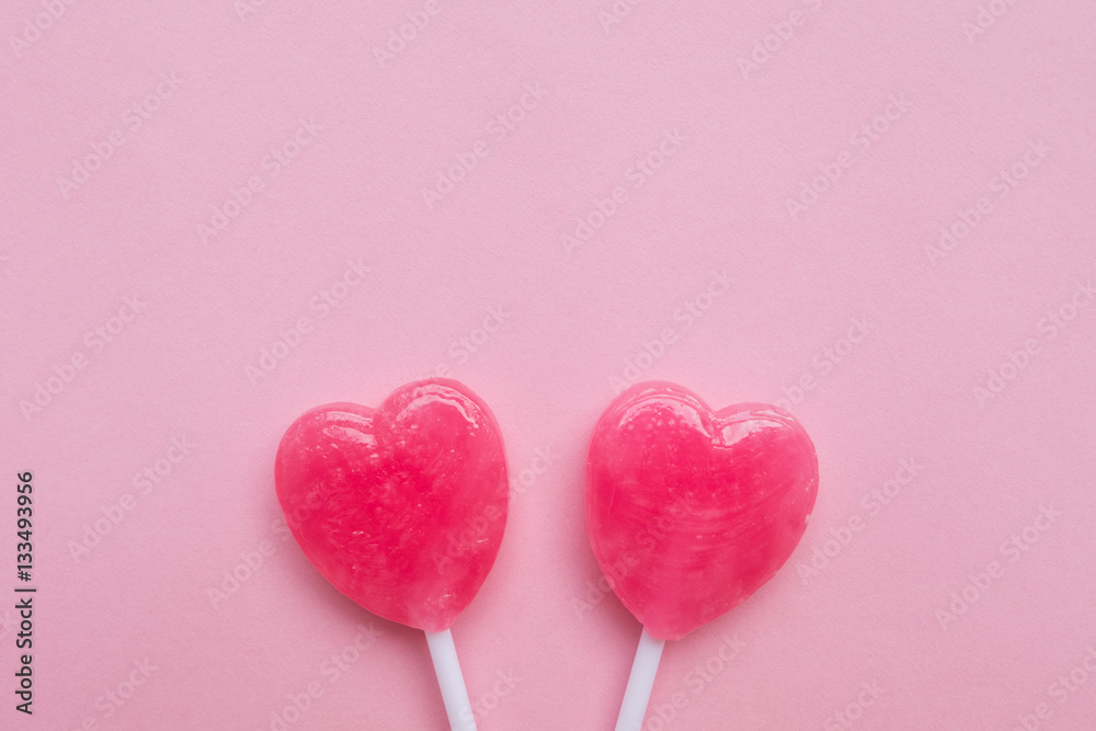two Pink Valentine's day heart shape lollipop candy on empty pastel pink paper background. Love Concept. Knolling top view. Minimalism colorful hipster style.
