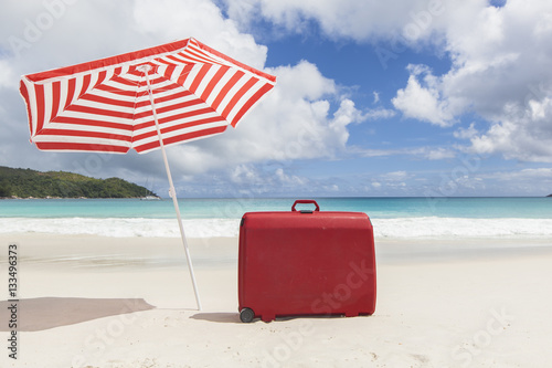 red suitcase under sunshade