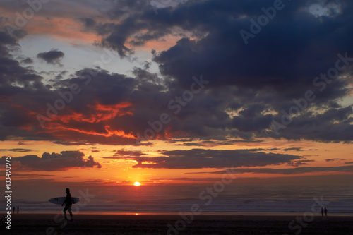 Surfer on the ocean beach at sunset or sunrise