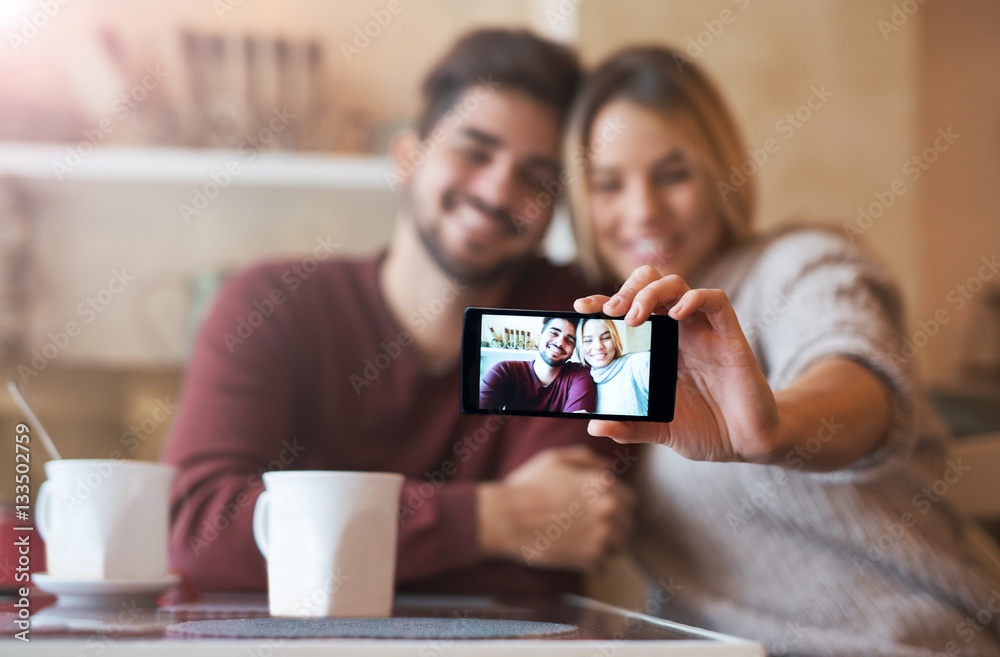 Beautiful young couple taking a selfie with smart phone in the c Beautiful young couple taking a selfie with smart phone in the c