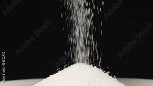 SLOW MOTION: Macro shot of falling of salt on a heap in a dish