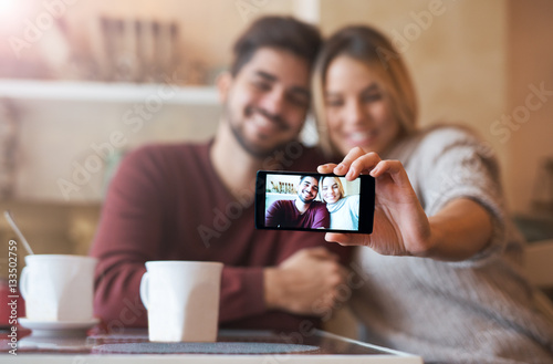 Beautiful young couple taking a selfie with smart phone in the c