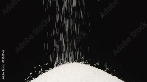 SLOW MOTION: Macro shot of falling of salt on a heap on a black background