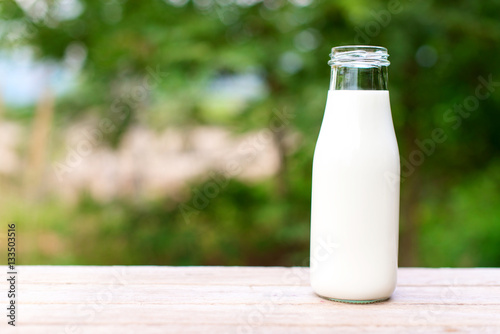 bottle of milk on wooden table with nature background.  