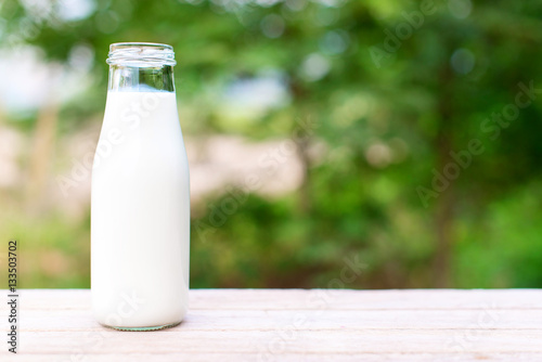 bottle of milk on wooden table with nature background.  