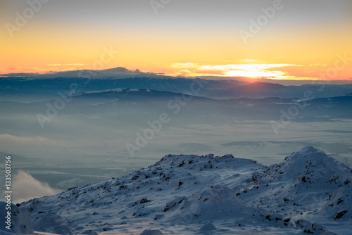 Sun dipping beyond the horizon - beautiful winter landscape on a mountain top