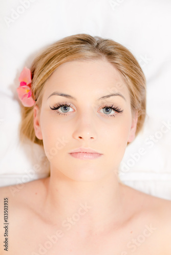 Attractive woman laying on massage spa bed white background  portrait closeup
