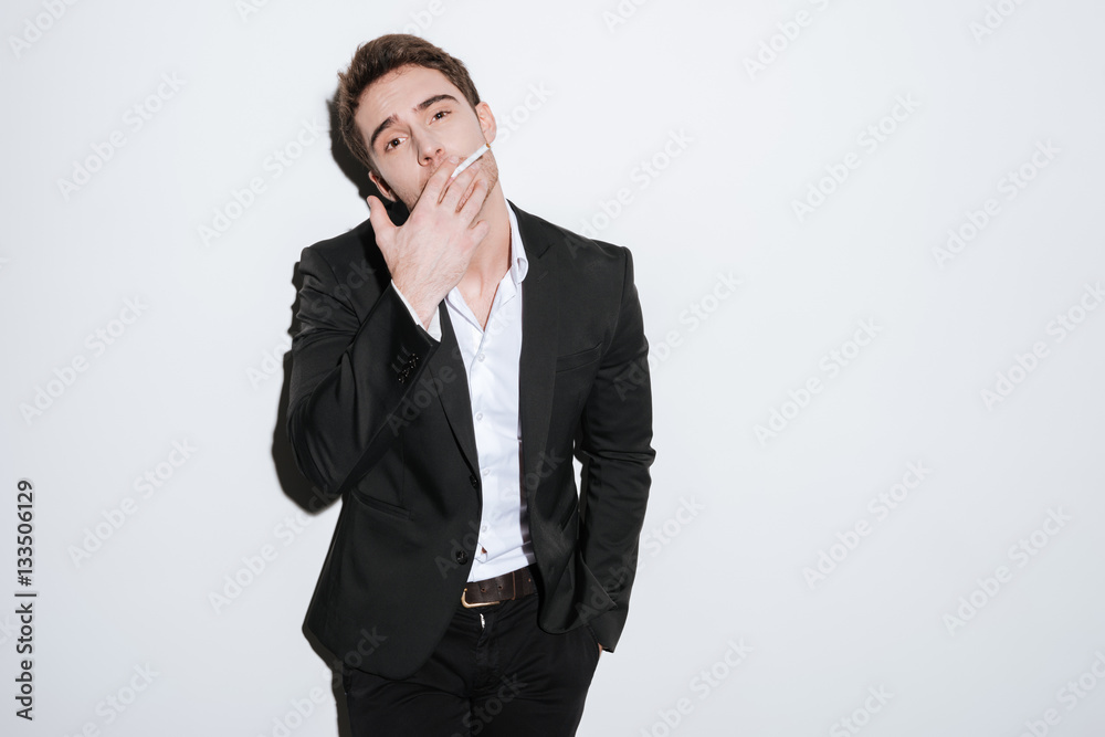 Attractive businessman posing at studio while holding cigarette. Attractive businessman posing at studio while holding cigarette.