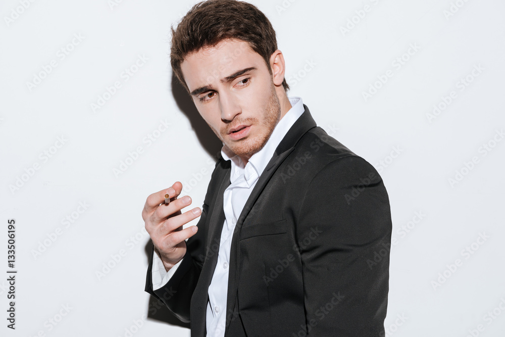 Serious young businessman posing at studio and look aside Serious young businessman posing at studio and look aside