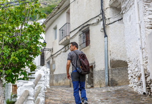 A tourist walks along a rustic street of a village