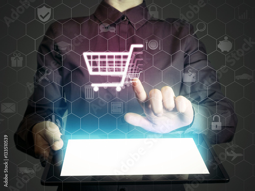 Image of a girl with a tablet in hands. She touches shopping cart icon.  Online shop concept.