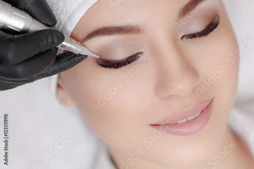 Cosmetologist making permanent make up at beauty salon
