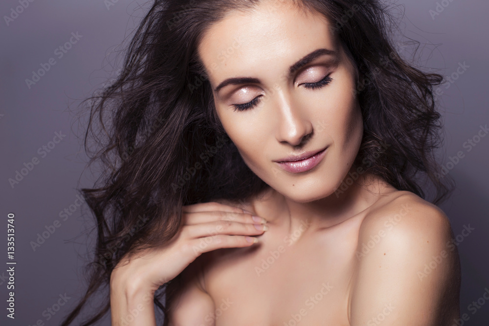 Beautiful brunette woman with clear fresh skin and curly hair on
