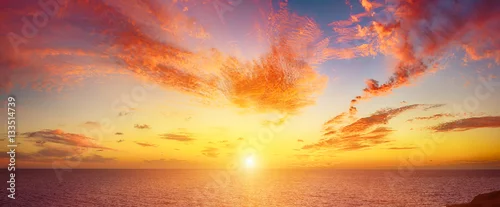 Obraz  z motywem Beautiful colorful sunset at the sea with dramatic clouds and sun shining. Beauty world natural outdoors travel background