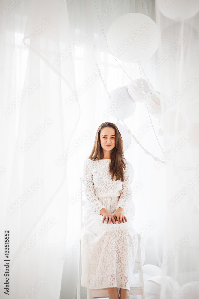 Gorgeous girl posing in a white dress standing in a white room Gorgeous girl posing in a white dress standing in a white room