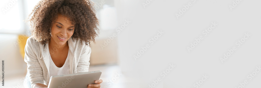 Relaxed mixed-race girl laying on floor connected with tablet Relaxed mixed-race girl laying on floor connected with tablet