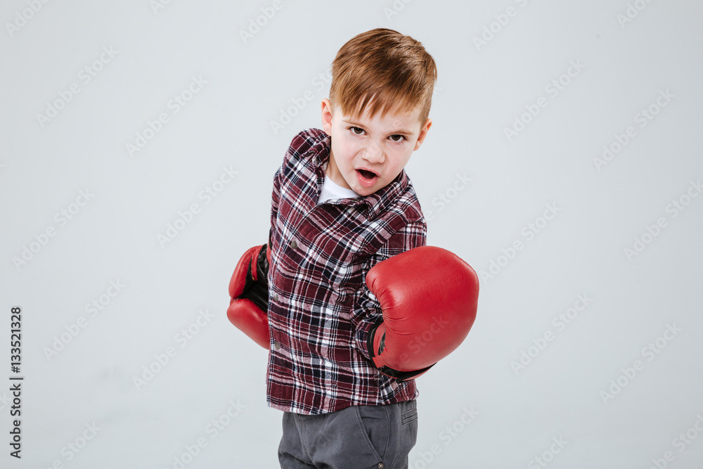 Cool little boy in red boxing gloves standing and training Cool little boy in red boxing gloves standing and training