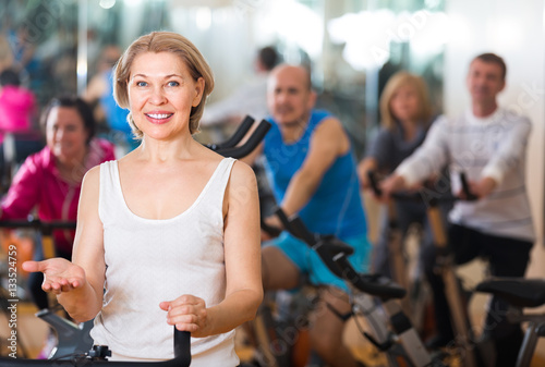 Elderly woman on fitness cycle in a gym. © JackF