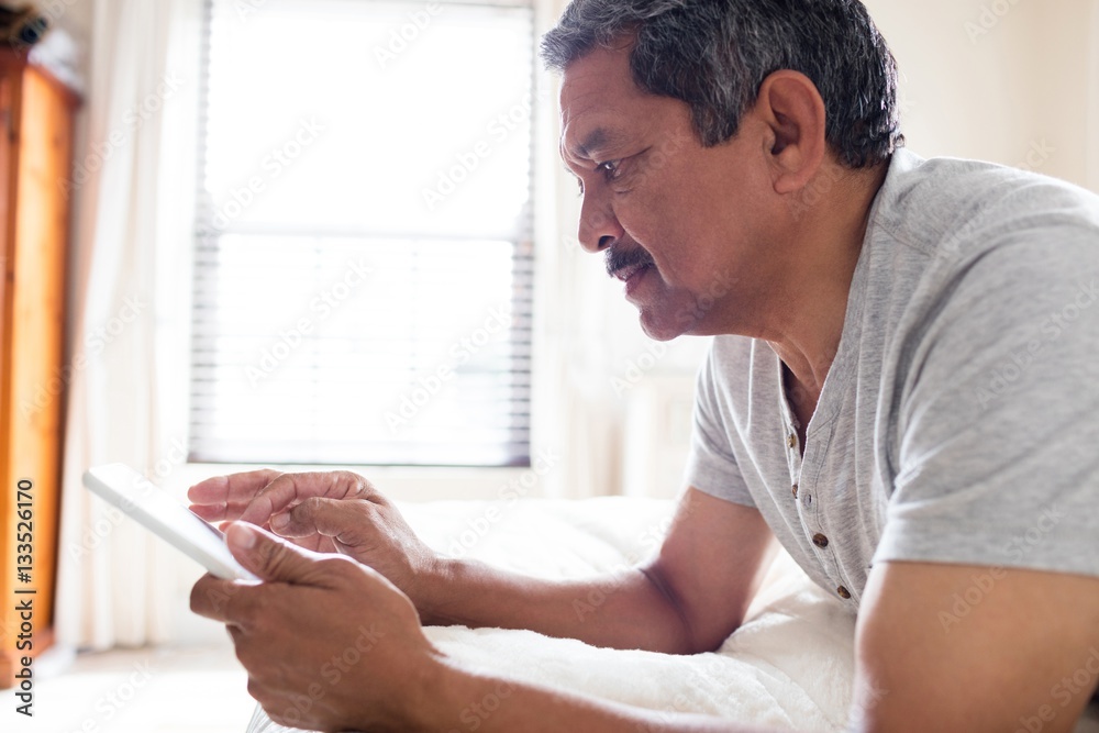 Senior man using digital tablet on bed