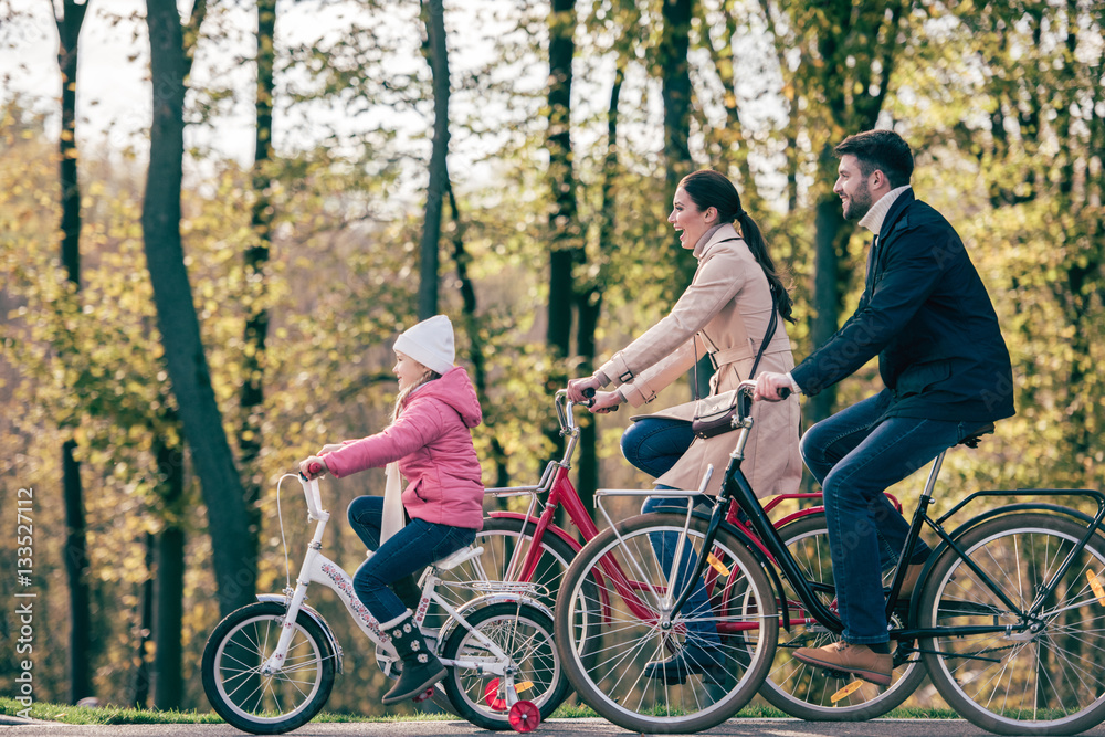 Obraz premium Happy family riding bikes in park