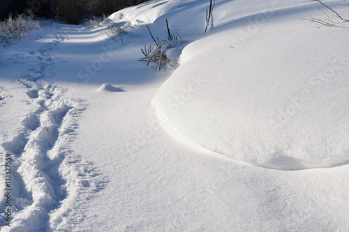 Human footprints in snow drifts on the road. photo