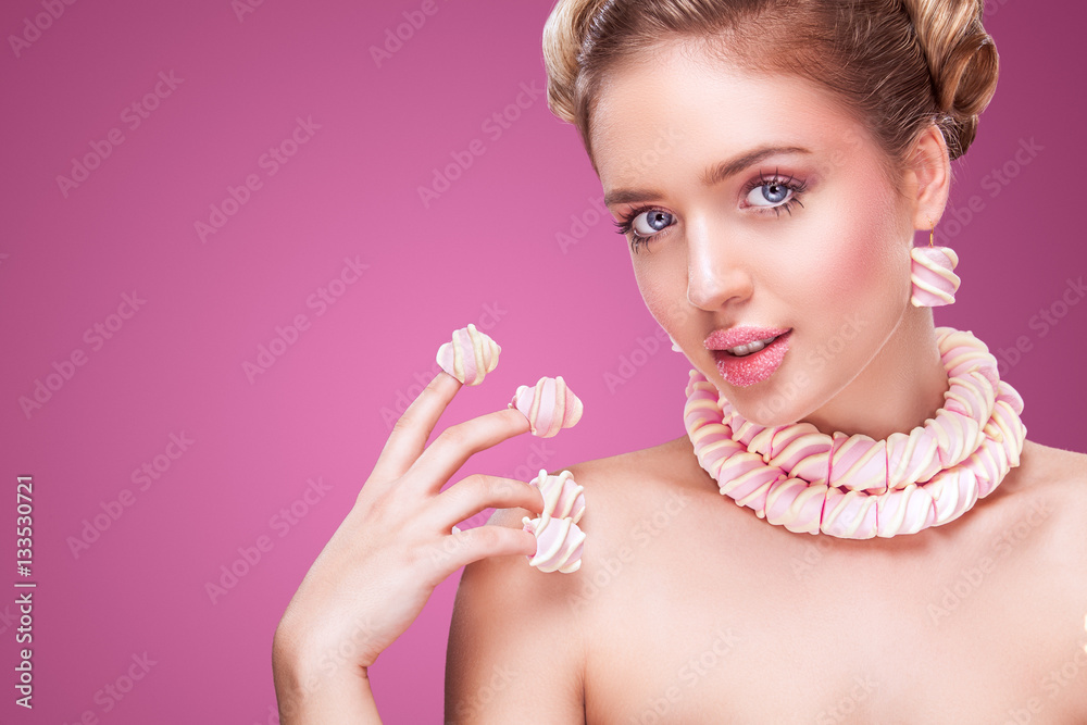 Attractive woman with lollipop in hand on pink background