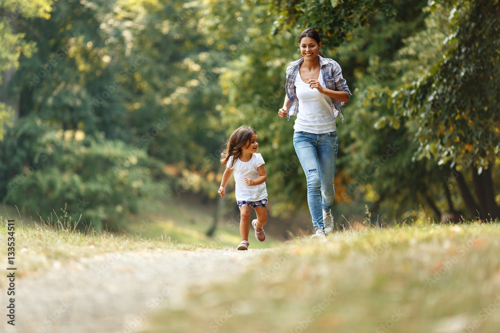 Mother and daughter playing and running around the park on beautiful morning. Mother and daughter playing and running around the park on beautiful morning.